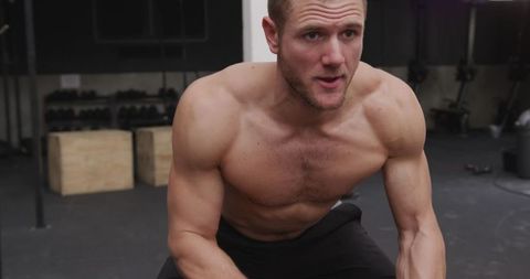 Shirtless male athlete using battle ropes for intense crossfit