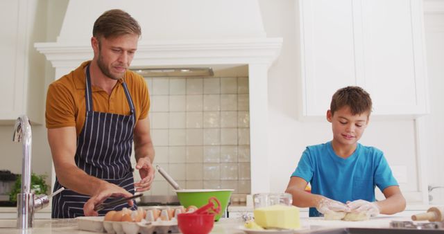 Caucasian father and son using digital tablet and baking together in the kitchen at home. family, love and togetherness concept