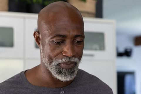 Senior african american man in modern kitchen looking thoughtful wearing gray henley