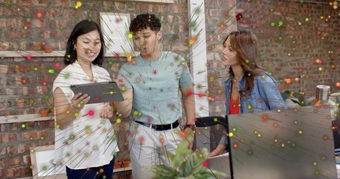 Creative team collaborating over tablet in modern brick studio with colorful motion overlay