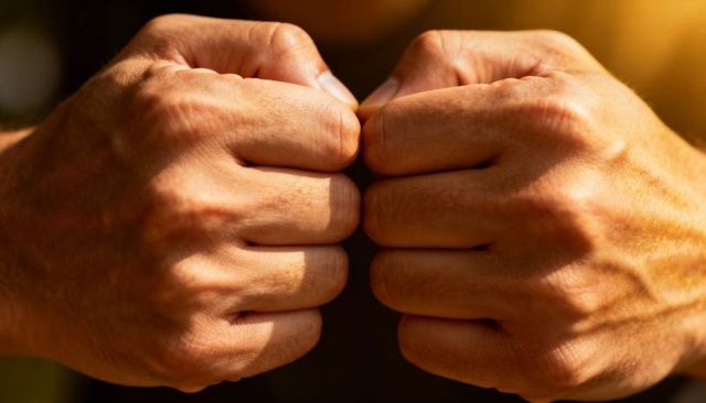 Clenching male fists showing knuckles veins skin texture in warm closeup lighting