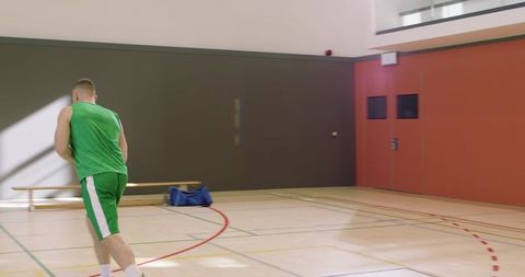 Male basketball player sprinting toward hoop in indoor gym practicing layup and teamwork