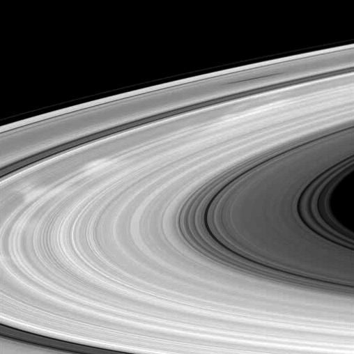 This captivating image shows the bright spokes and the shadow of a moon on Saturn's B ring as captured by NASA's Cassini spacecraft. Scientists are still studying the radial markings known as spokes, which are visible stretching from the far left to the upper right. Ideal for educational materials, space exploration articles, and astronomy enthusiasts.