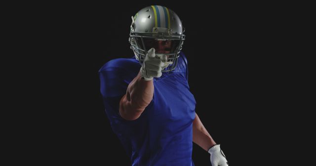 Confident American football player wearing helmet and uniform, pointing directly towards camera. Image ideal for articles about sportsmanship, team motivation, and athletic marketing campaigns. Can also be used in promotional materials for football events, sports gear advertisements, or athletic empowerment features.