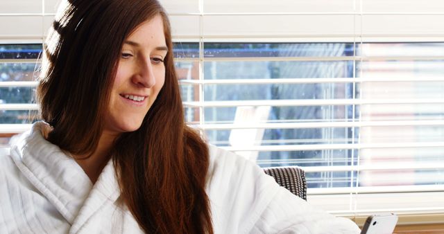 Woman Relaxing in Robe with Smartphone in Natural Light - Download Free Stock Images Pikwizard.com