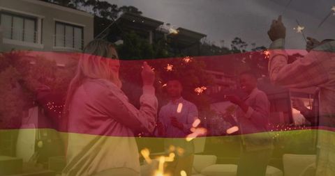 Friends celebrating outdoors with sparklers at dusk