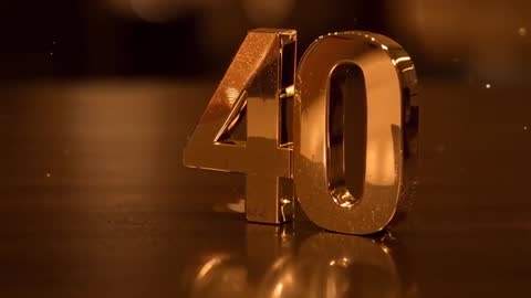 Gold 40 numeral reflecting on tabletop with drifting dust and warm amber bokeh