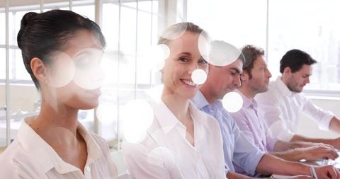 Smiling woman leading collaborative team at bright modern glass office workstation
