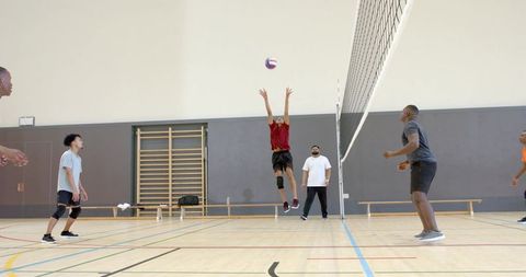 Indoor volleyball jump block and spike by african american player in mixed team practice