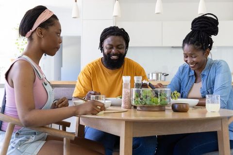 African american family sharing joyful meal around round wooden table in bright kitchen