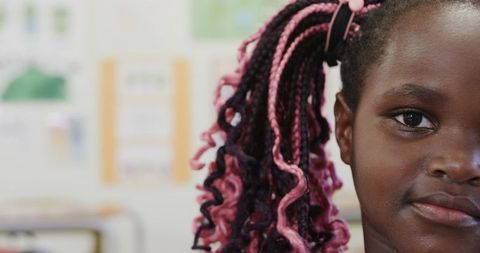 Child with Pink Braids Displaying Inquisitive Look in Classroom