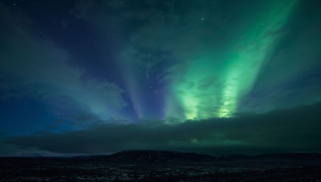 Aurora Borealis Dancing Over Arctic Plain with Green and Purple Light Curtains Night Sky