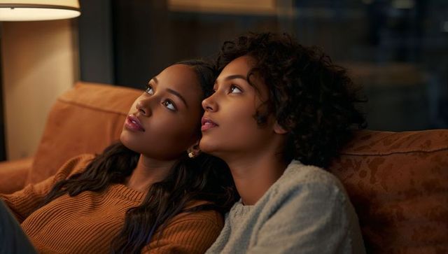 Evening intimacy two women gazing on couch cozy lamp-lit moment of quiet connection