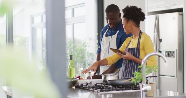 Image of happy african american couple cooking together with tablet. Love, relationship and spending quality time together concept.