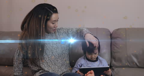 Mother and Son Enjoying Tablet Time on Couch with Magical Light Effect