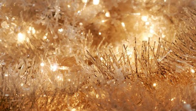 Golden tinsel and warm LED lights creating glittering bokeh holiday sparkle closeup