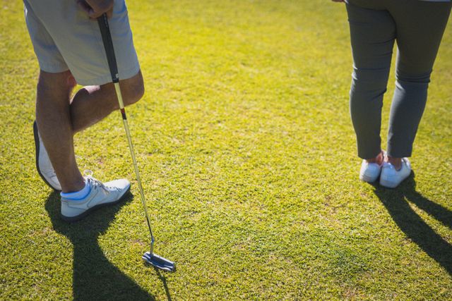 Caucasian couple standing on a golf course, with the man leaning on a golf club. Ideal for promoting golf courses, retirement communities, healthy lifestyles, and outdoor hobbies. Suitable for use in advertisements, brochures, and websites related to sports and leisure activities.