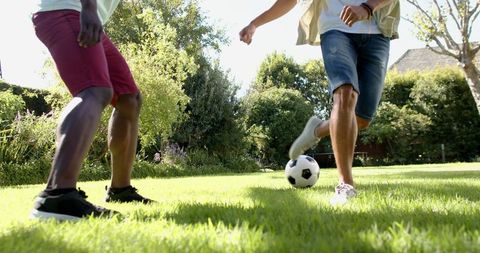 Diverse Male Friends Playing Soccer in Sunny Backyard
