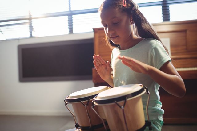 Girl playing bongo drums in classroom at music school