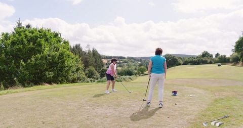 Female Golf Companions Practicing Shots in Scenic Landscape