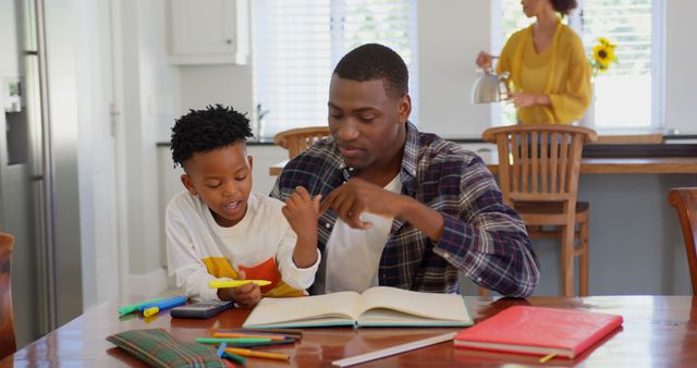 Father helping son with homework at dining table in family home - Download Free Stock Images Pikwizard.com