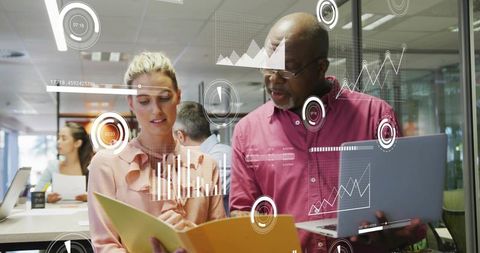 Collaborating and analyzing data with laptop and documents in modern open-plan office