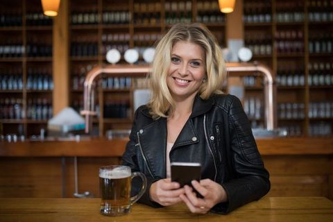 Woman in Black Leather Jacket Relaxing in Pub with Smartphone - Download Free Stock Images Pikwizard.com