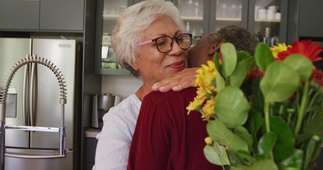 Senior Couple Hugging with Flower Bouquet in Modern Kitchen - Download Free Stock Images Pikwizard.com