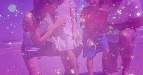 Family kneeling with children on beach surrounded by purple bokeh lights and sparkle