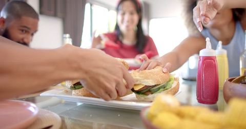 Friends Reaching for Sandwiches at Cozy Home Gathering