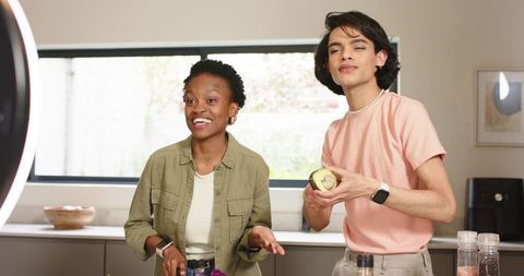 Two Diverse Creators Filming Cooking Tutorial in Bright Modern Kitchen with Ring Light