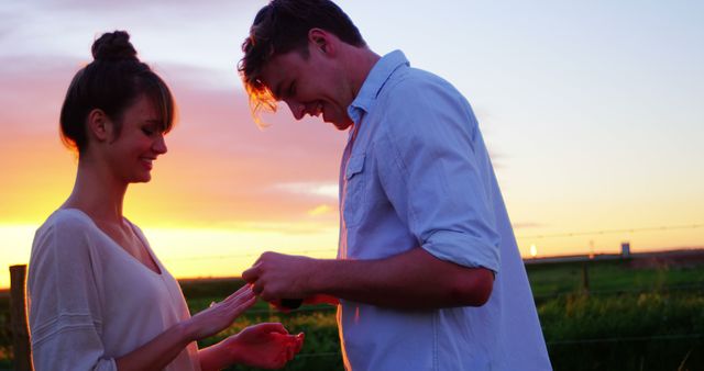 A young Caucasian couple enjoys a romantic moment together at sunset, with copy space. Their affectionate interaction against the vibrant sky creates a picturesque and intimate atmosphere.