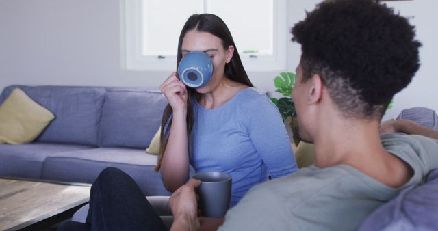 This video shows a happy biracial couple sitting on a sofa in a cozy living room while enjoying coffee together. The relaxed setting and intimate moment make it perfect for themes related to couple bonding, leisure activities, and homely environments. Ideal for use in advertisements, blog posts, or social media promoting relationships, home interiors, or lifestyle brands.