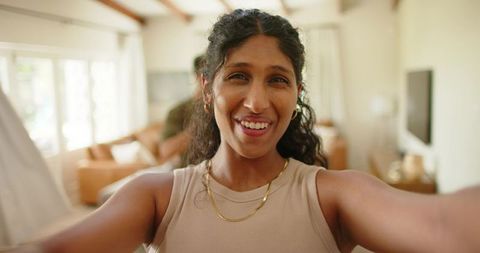 Smiling african american woman taking selfie in cozy modern living room with happy partner
