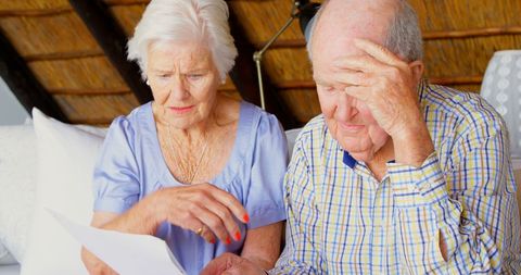 Senior couple anxiously discussing household finances and bills