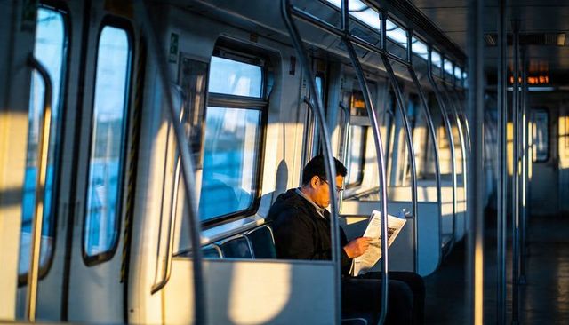 Sunlit commuter reading newspaper on train during golden hour city commute and solitude