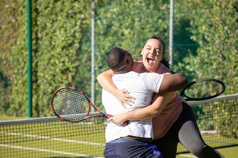 Teammates celebrating tennis victory with joyful hug