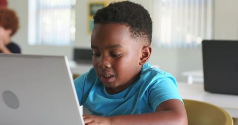 African American boy working on laptop in classroom concentrating on digital learning