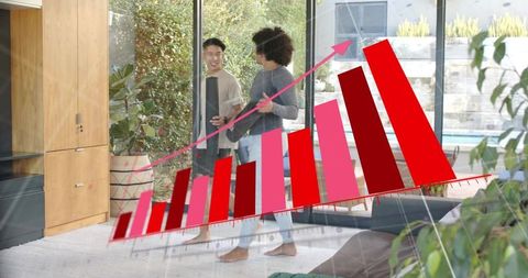 Young men walking into sunlit living room carrying slim device with rising red bar chart