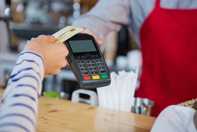Woman making payment through credit card at counter in cafÃ©