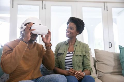African American Couple Using VR Headset at Home, Smiling and Relaxing