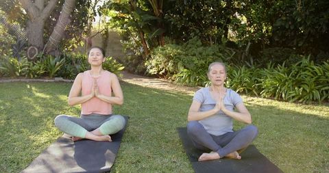 Mother and Daughter Practicing Yoga Meditation in Backyard Garden