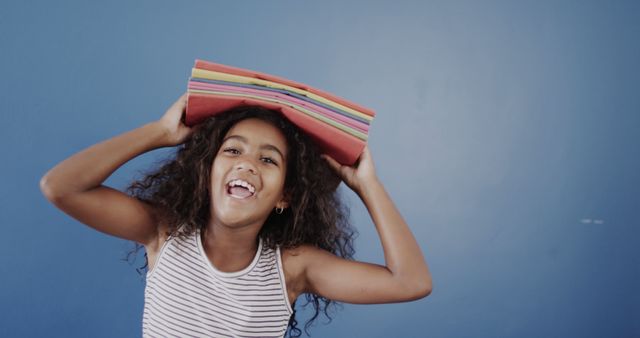 Joyful child balancing colorful papers on head laughing - Download Free Stock Images Pikwizard.com