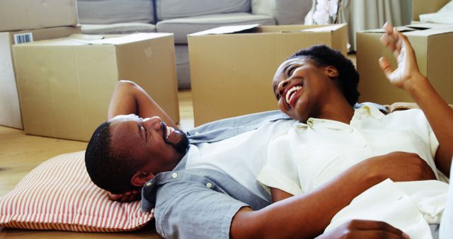 Happy couple relaxing on floor surrounded by moving boxes in new home - Download Free Stock Images Pikwizard.com