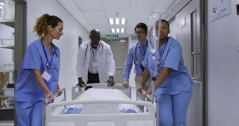 Medical team rushing patient on gurney through hospital corridor with iv stand