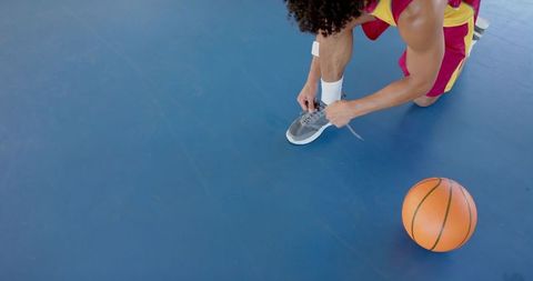 Athlete Tying Sneakers on Basketball Court, Preparing for Game