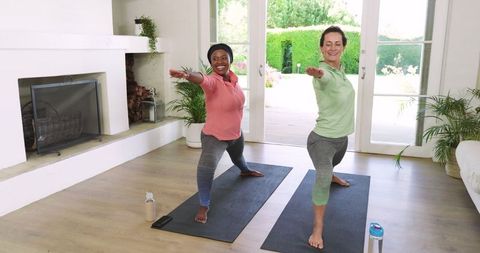 Diverse friends doing yoga at home in sunlit room