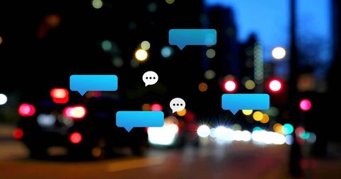 Blue Chat Bubbles Floating Over Urban Night Street with Bokeh Car Lights