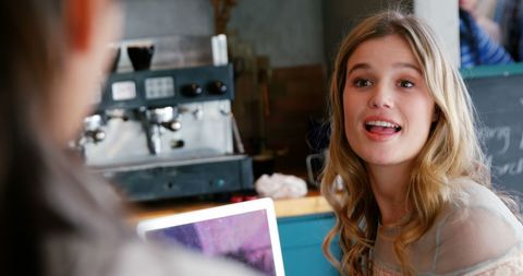 Young caucasian woman engaging in cheerful coffee shop conversation