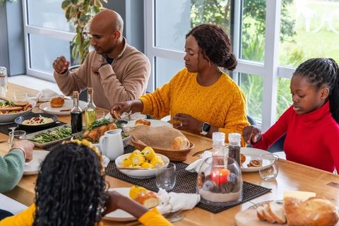 African american family sharing holiday roast around sunlit wooden dining table